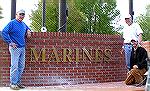 Marine Bill Rakow, project manager for the Veterans Memorial standing at right and two workers installing bronze letters, pose in front of the just completed lettering for the Marines memorial wal.