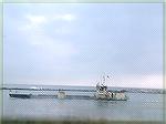 Not such a great photo taken at Harrison's Harbor Watch of a boat in the inlet that seemed to be dredging for something and the water washed up and maybe filtered on the low part of the bow.  What cou