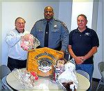 On behalf of the Ocean Pines Anglers Club Art Sachs and Walt Boge present toys to Lt. Smack of the Worcester County Sheriffs Department. The toys will be used by first responders to calm children invo