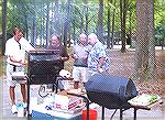 Angler Budd Heim [L] samples the results of anglers grillmen Harry Doan, Joe Hoover and Tom Edmundson at the first combined picnic of the Ocean Pines Anglers Club and the Maryland Saltwater Sportfishe