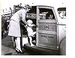 Eleanor Barnes, Red Cross volunteer during WW II shown helping son Jack Jr into Red Cross motolr pool vehicle in San Diego.