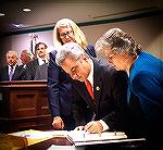 Chip Bertino signs the "book" to officially become the new Worcester County Commission representing Ocean Pines District 5 as Susan Bertino, right, looks on.